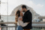 Couple leaning in for a kiss with ocean backdrop during playful engagement session