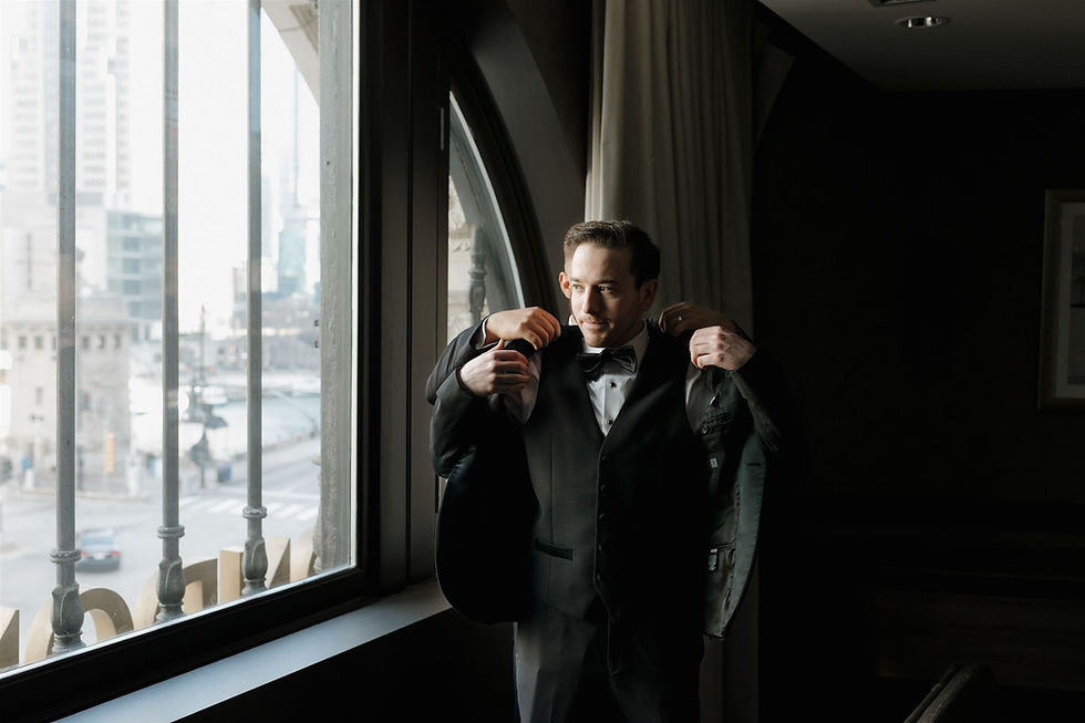 Groom putting on suit jacket photographed by MacKenzie Rana