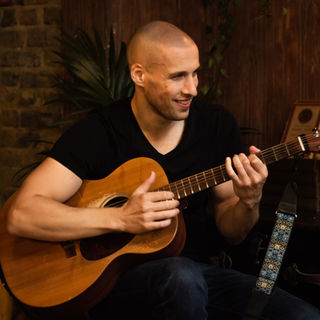 Tatum Marshall singer and guitarist sat down with a guitar smiling while playing an acoustic set