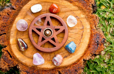 Wood pentagram incense holder with eight various gemstones on a tree stump.