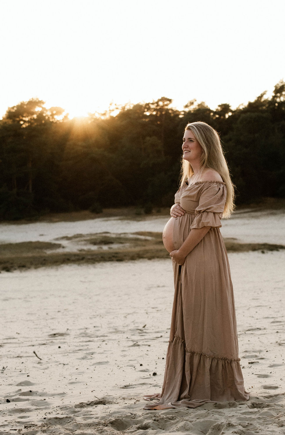Zwangerschapsshoot op zandvlakte in Twente met zwangere vrouw in lange beige jurk
