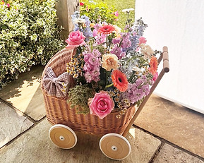 Events flowers, a bright and summery floral arrangement in a wicker pram for a baby shower