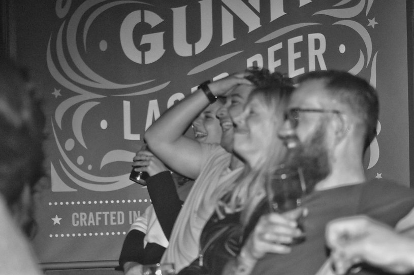 People laughing at a comedy night, and drinking beer.