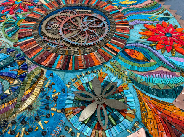 Circular mosaic artwork: gears, flowers, vibrant colours