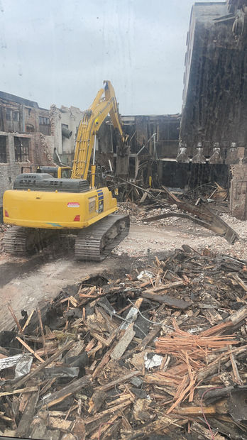 Piles of rubble, wood, and stone can be seen during the demolition process done by Brophy Excavation.