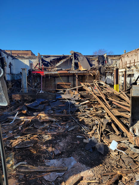 The inside of a demolished building where piles of rubble, destroyed wood, and home materials lay.