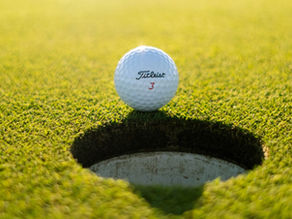 Golfbold på kanten af et hul, som symbol på problemer i en tandklinik ikke altid løses så nemt