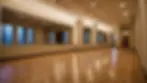 Wide angle view of a dance studio with wooden floors and mirrors