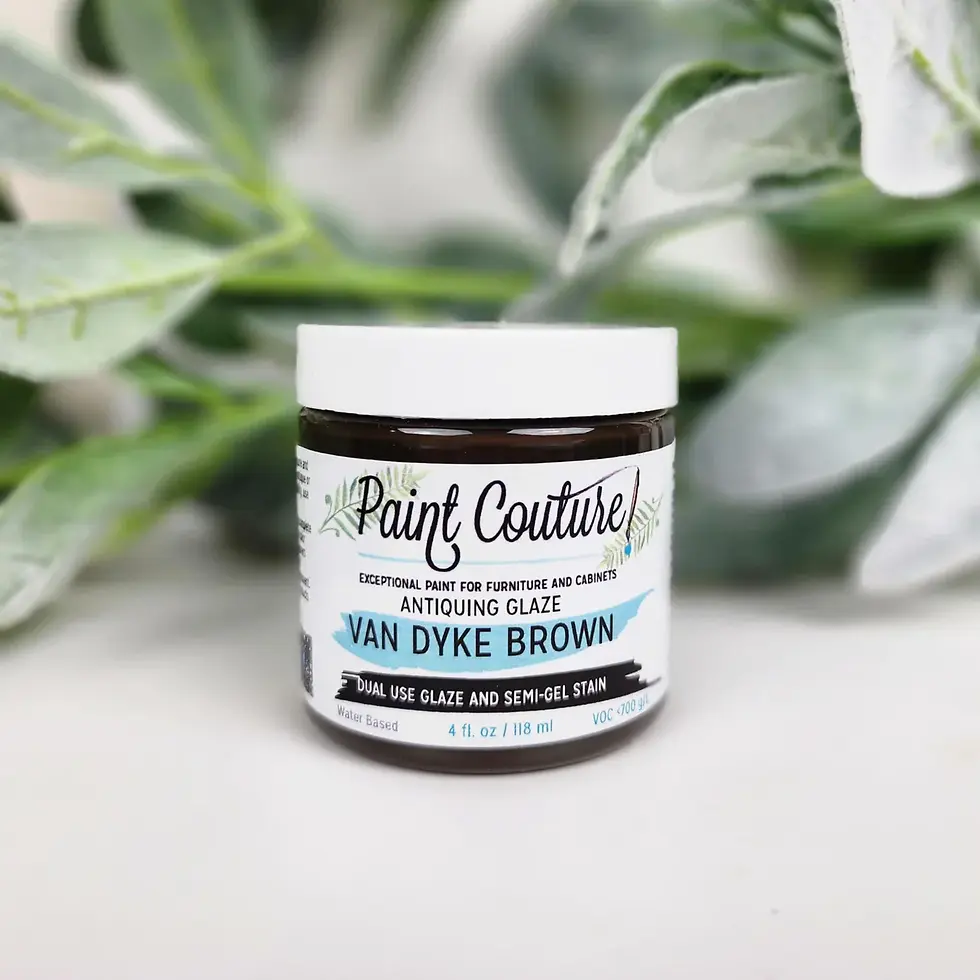 Paint Couture! ANTIQUING GLAZE VAN DYKE BROWN jar foregrounding green leaves.