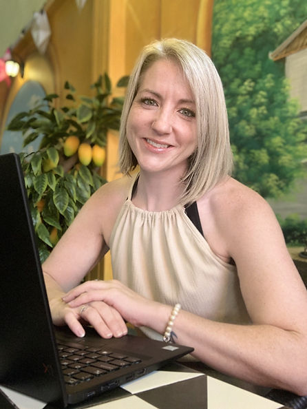 Lucy Joy Knight sitting at a laptop, smiling gently—therapeutic coach and counsellor in a warm, safe online environment