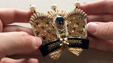 Decorative embroidered crown element with beads, sequins, purl wire, and velvet ribbon.
