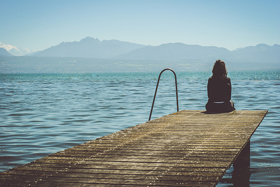 Woman Sitting At The End of a Dock