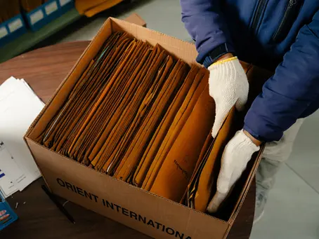 An Orient Relocation employee carefully organizes files in labeled boxes for secure business records storage.