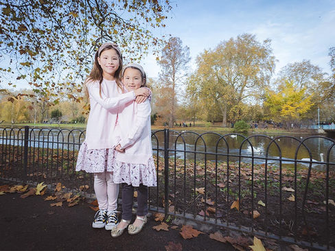 Two young sisters posing together by the lake with swans in St. James's Park, London.