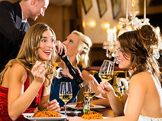Three people dining and drinking wine at an elegant restaurant with an ornate chandelier, perfect for promoting high-end London corporate Christmas party photography, holiday gala documentation, and event coverage.