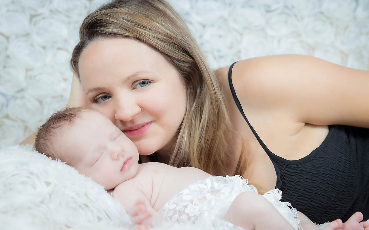 Mother resting beside her sleeping newborn baby during a calm newborn photography session in London, captured with gentle composition and beautifully crafted light.