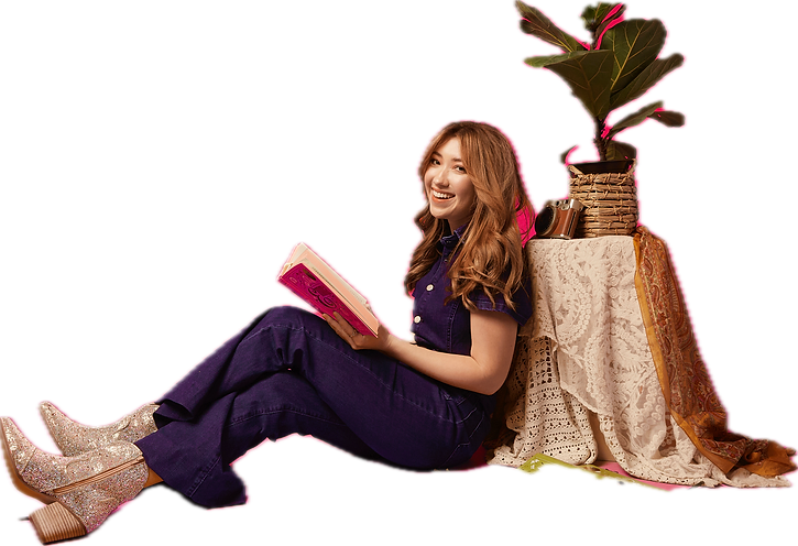 Indie artist sits with a book against a tree.