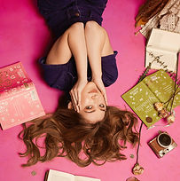 Pop artist lying upside down surrounded by books