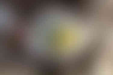 mud kitchen enamel bowl with mud, buttercups and a dandelion