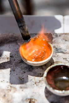 A crucible with liquid metal inside and fire coming out the top