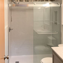 Tub to shower conversion with smooth Onyx walls, low threshold shower base, tile accent, crown molding, recessed caddy, brushed nickel shower fixtures and bypass shower door with clear glass. 