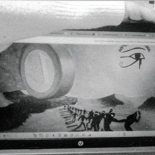 Quadro in bianco e nero di Flavio Ferrarini "Nuovi schiavi", occhio stile egizio nel cielo con una grande moneta che viene trainata da uomini nel deserto