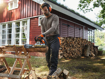 man cutting logs at home with a STIHL chainsaw and Stihl wooden saw hourse