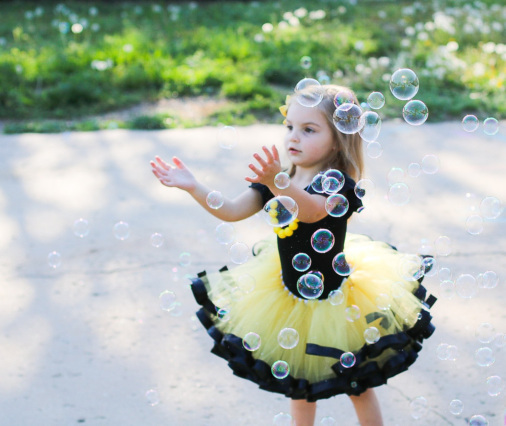 little girl in a tutu playing with bubbles
