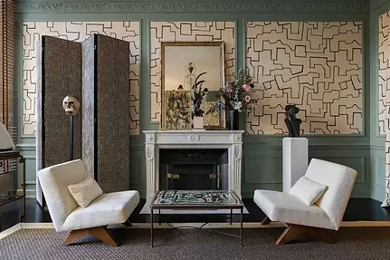 Elegant room decor with white chairs, art and patterned walls.