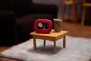A frame from a stop motion film with a coffee table holding a vase and framed photo of a wisp