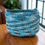 Thumbnail: Blue and gray crocheted basket on wooden table, Amish Baskets and Beyond.