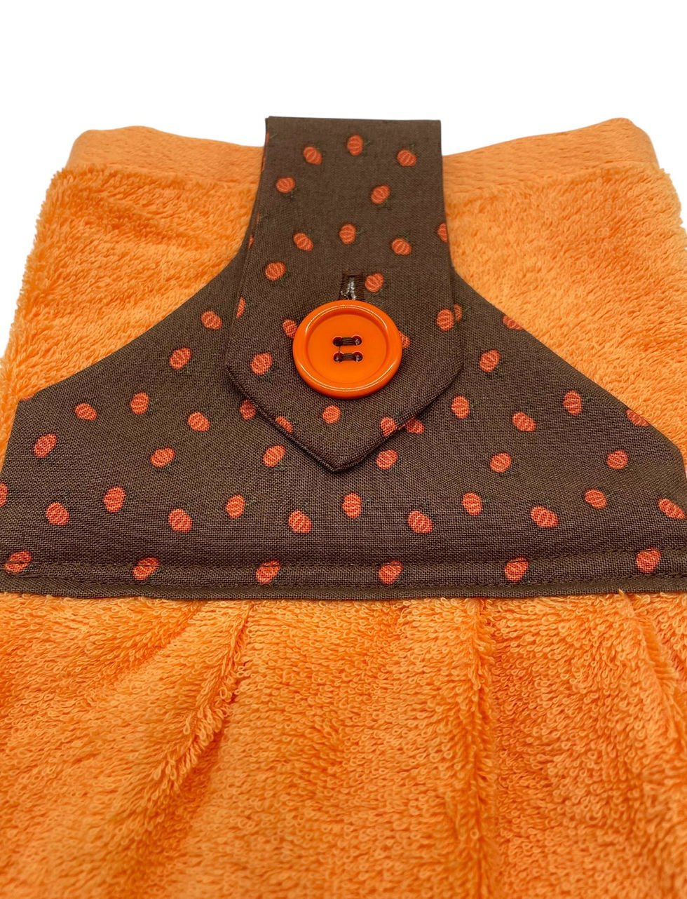 Thumbnail: Orange towel with brown polka dot hanging loop and orange button