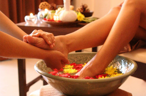 mergulhar os pés na água morna com ervas revigorantes e sal grosso