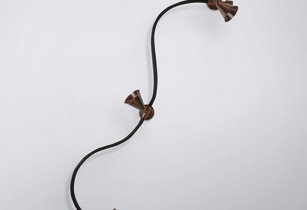 Adjustable spotlight bar with three brass conical shades and leather-wrapped bar, perfect for artwork lighting.