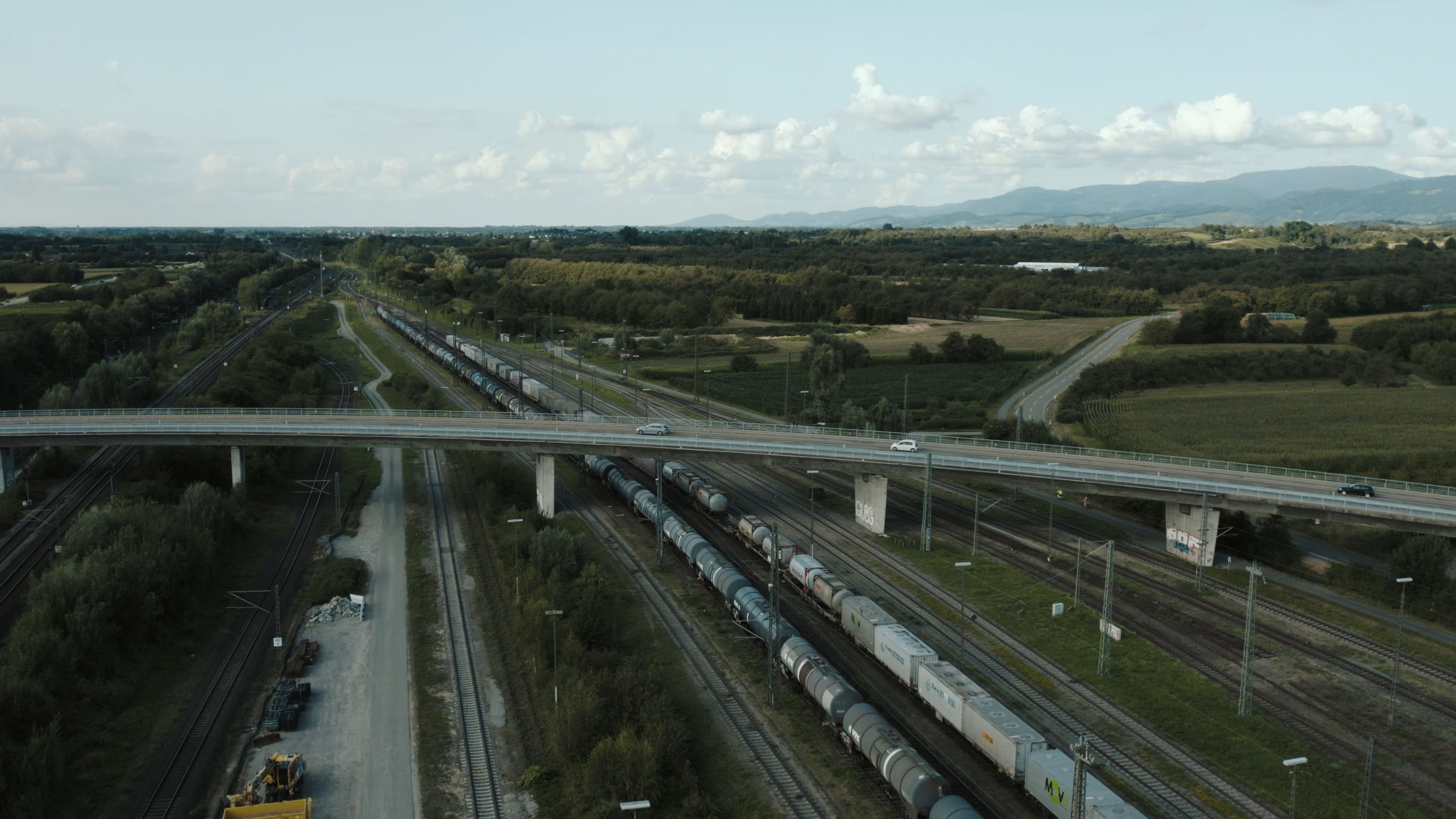 貨物列車とコンテナ輸送の俯瞰風景。イラン自動車・鉄道部門への米制裁と国際物流・部品取引を示すイメージ