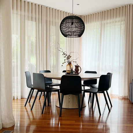 Round dining table with linen sheers and pendant lighting