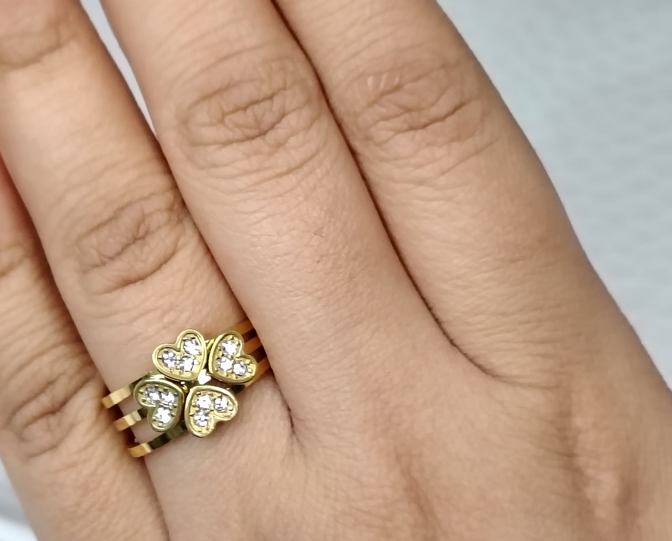 Gold four-leaf clover ring set with diamonds on a finger