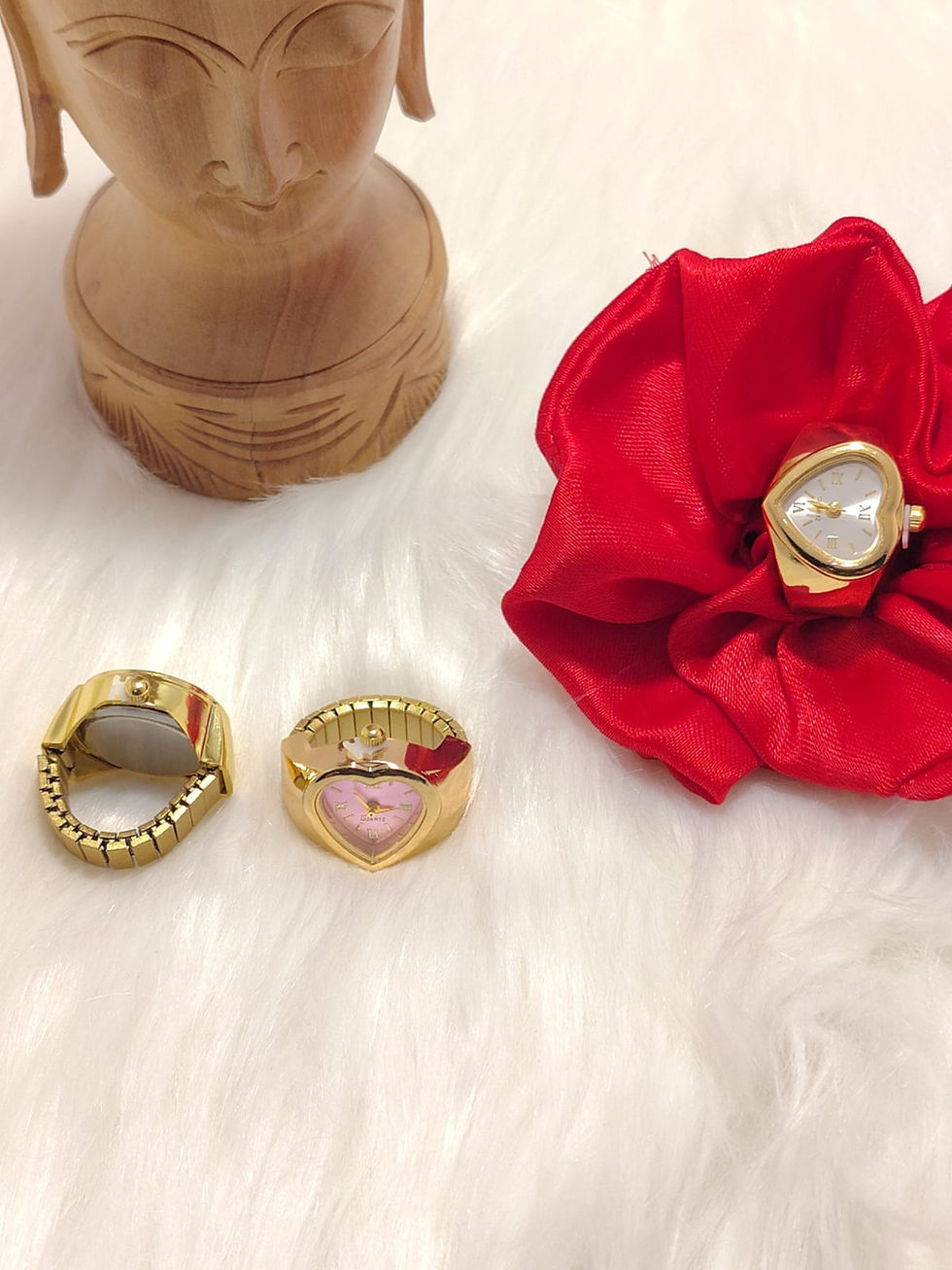 Three gold heart shaped ring watches on white faux fur
