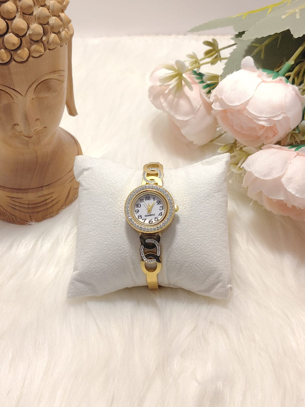 Gold Bracelet Watch 5 on a white pillow with flowers