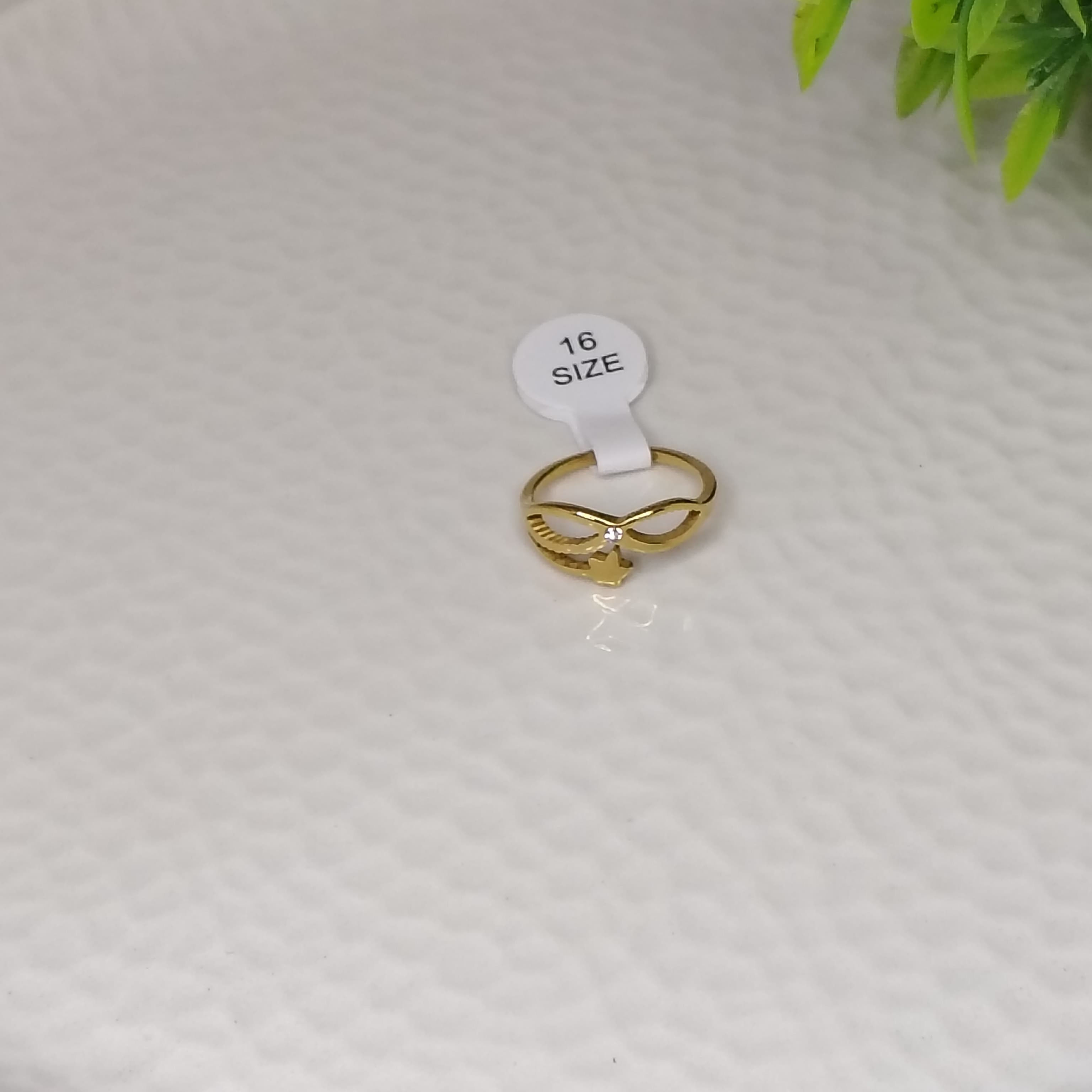 Gold Shining Star Ring with size 16 tag on white surface