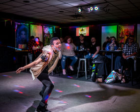 A man with a silver glitter beard performing drag