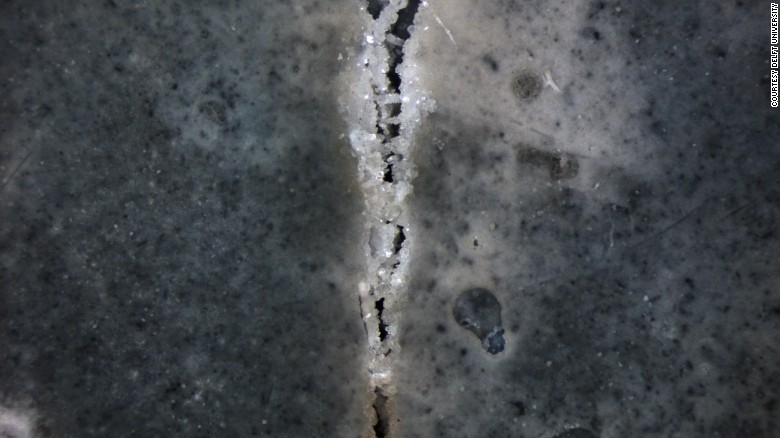 Dark slab of concrete with crack that you can see crystalizing to heal itself