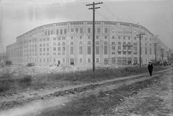 Yankee Stadium circa 1923 with man walking down dirt road next to it
Description automatically generated