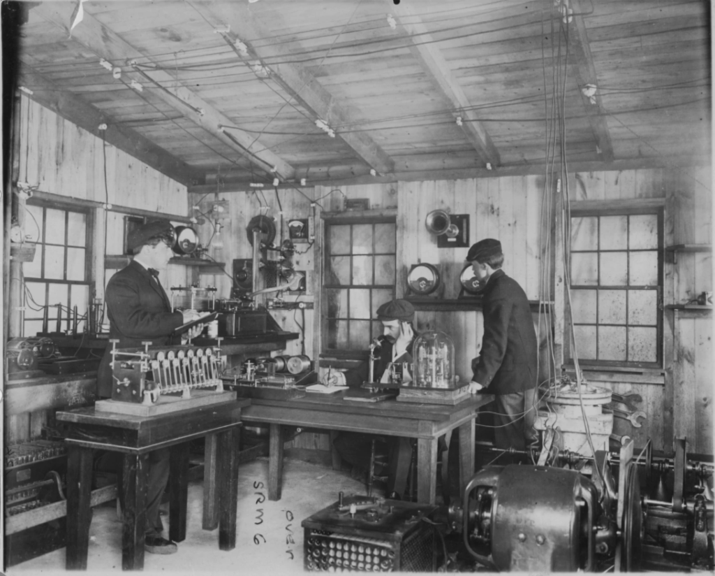 Fessenden (center) working in one of Thomas Edison’s labs. (Image source)
