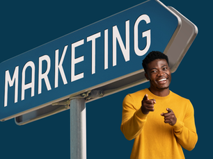 A young black man in a yellow jumper points at the camera. He is positioned in front of a large street sign that says: "Marketing". The background is a dark blue.