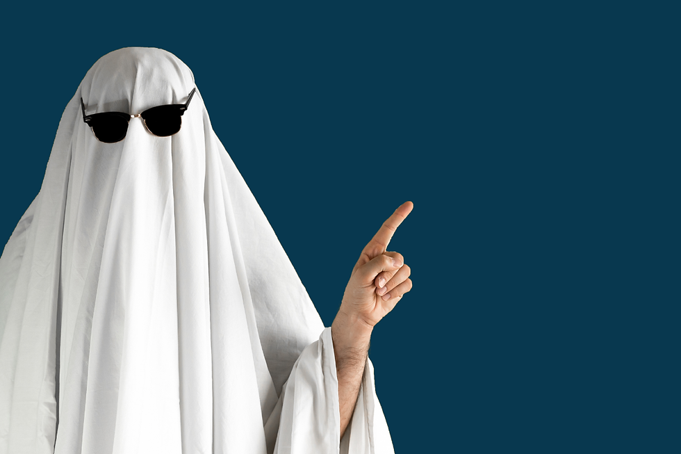 A person in a white sheet ghost costume with sunglasses points upwards. The background is a solid dark blue, creating a playful mood.