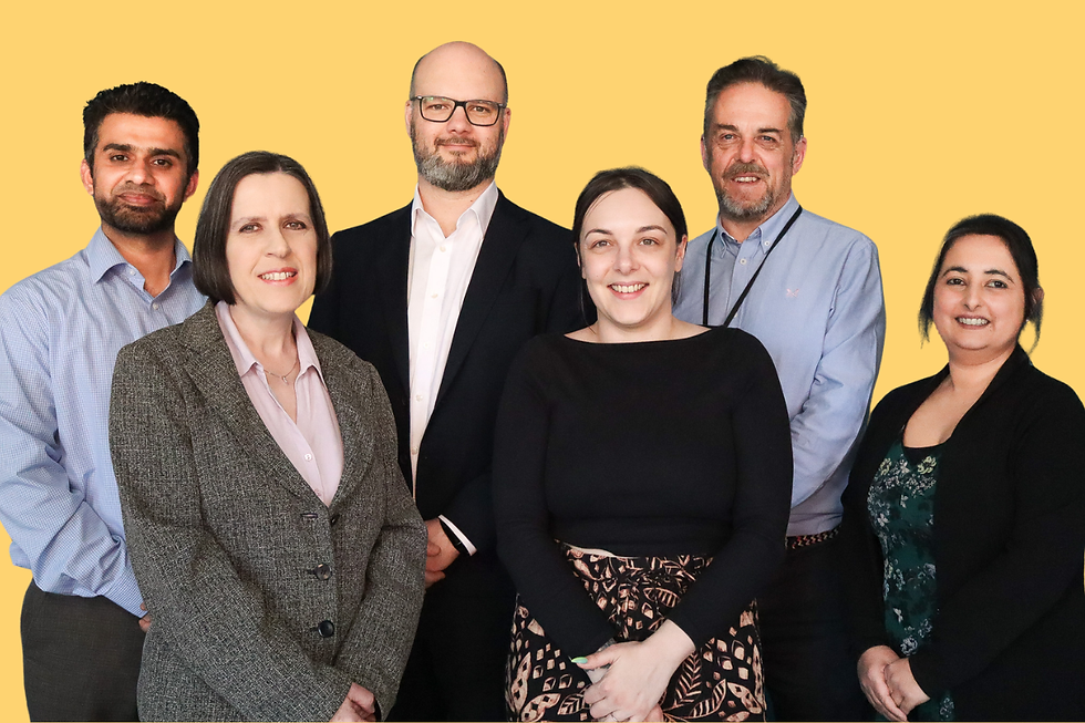 Six smiling coworkers pose in a group portrait against a plain yellow background.