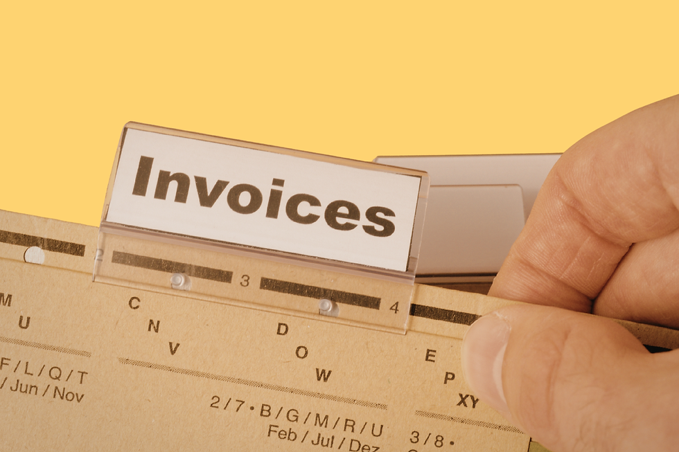Hand organizing file folders labeled "Invoices" against a yellow background, highlighting a simple filing system.