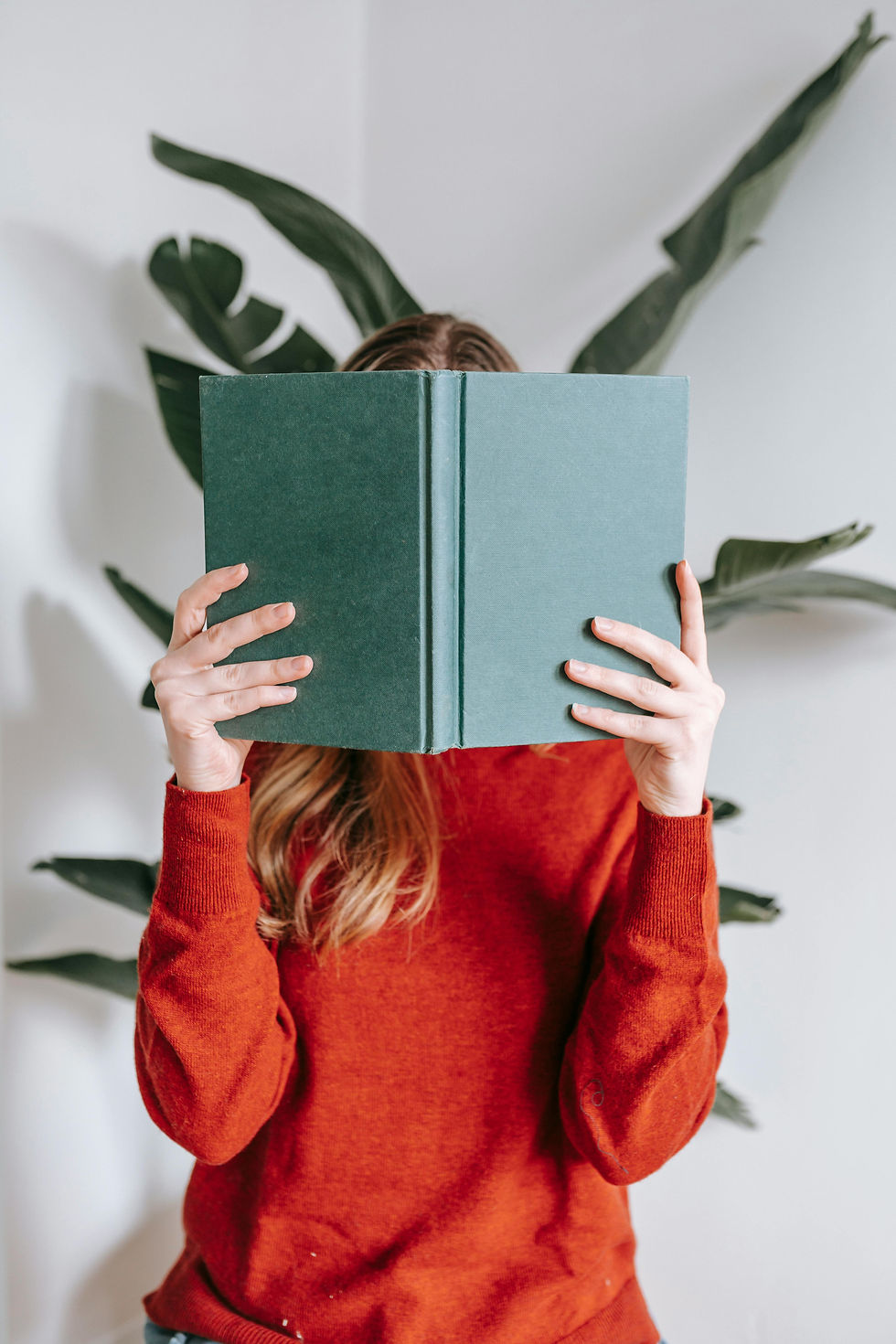 Ein Mädchen hält sich ein grünes Buch vors Gesicht