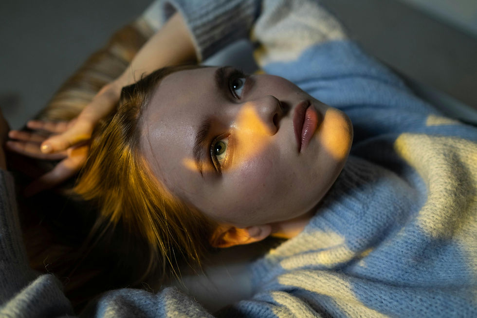 Junge Frau liegt in Gedanken versunken auf dem Sofa